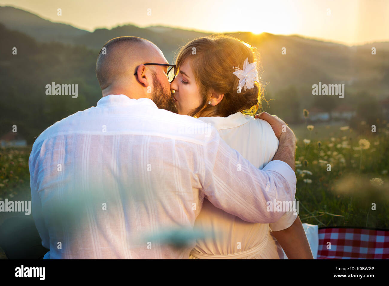 Couple kissing on picnic with romantic sunset view Stock Photo
