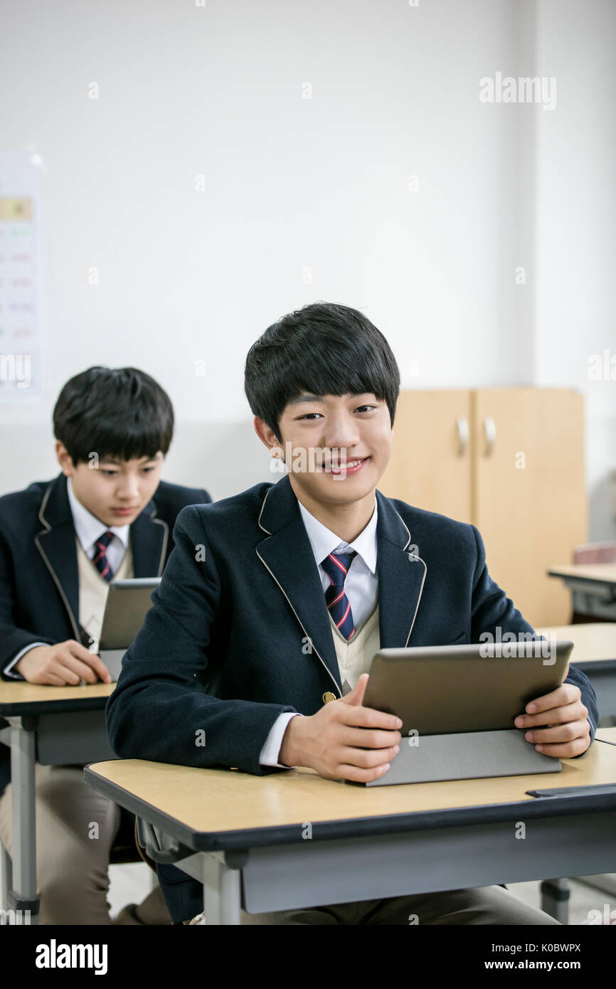 Smiling school boy and his classmates with electric tablets Stock Photo