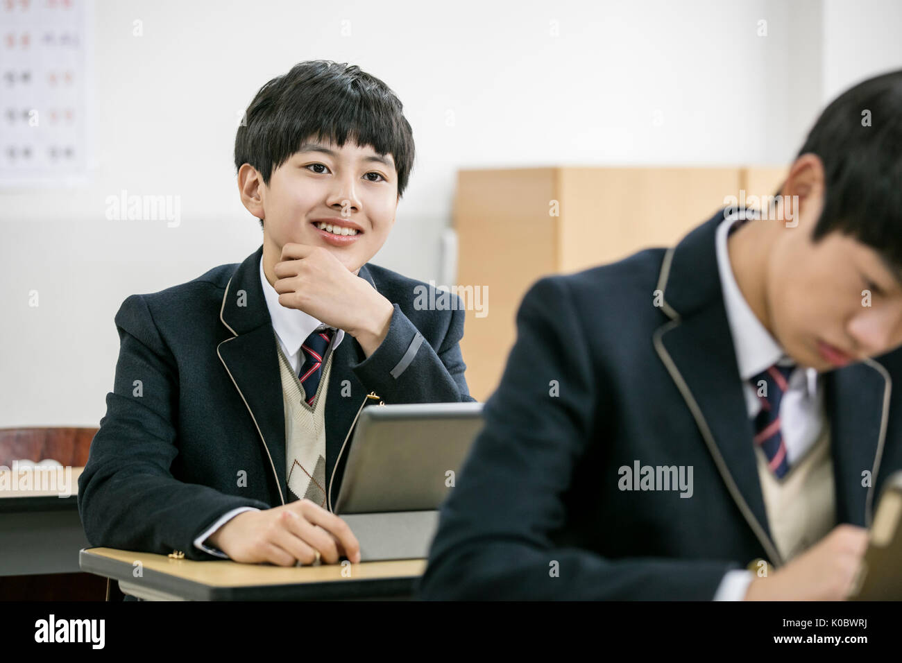 Portrait of smiling school boy with electric tablet and his classmate Stock Photo