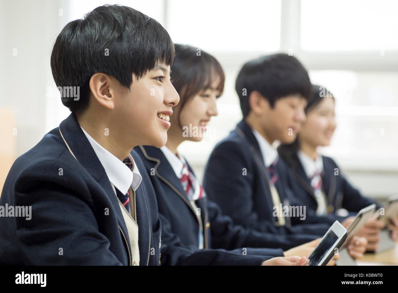 Side view portrait of smiling school boy and his classmates with electric tablets taking class Stock Photo