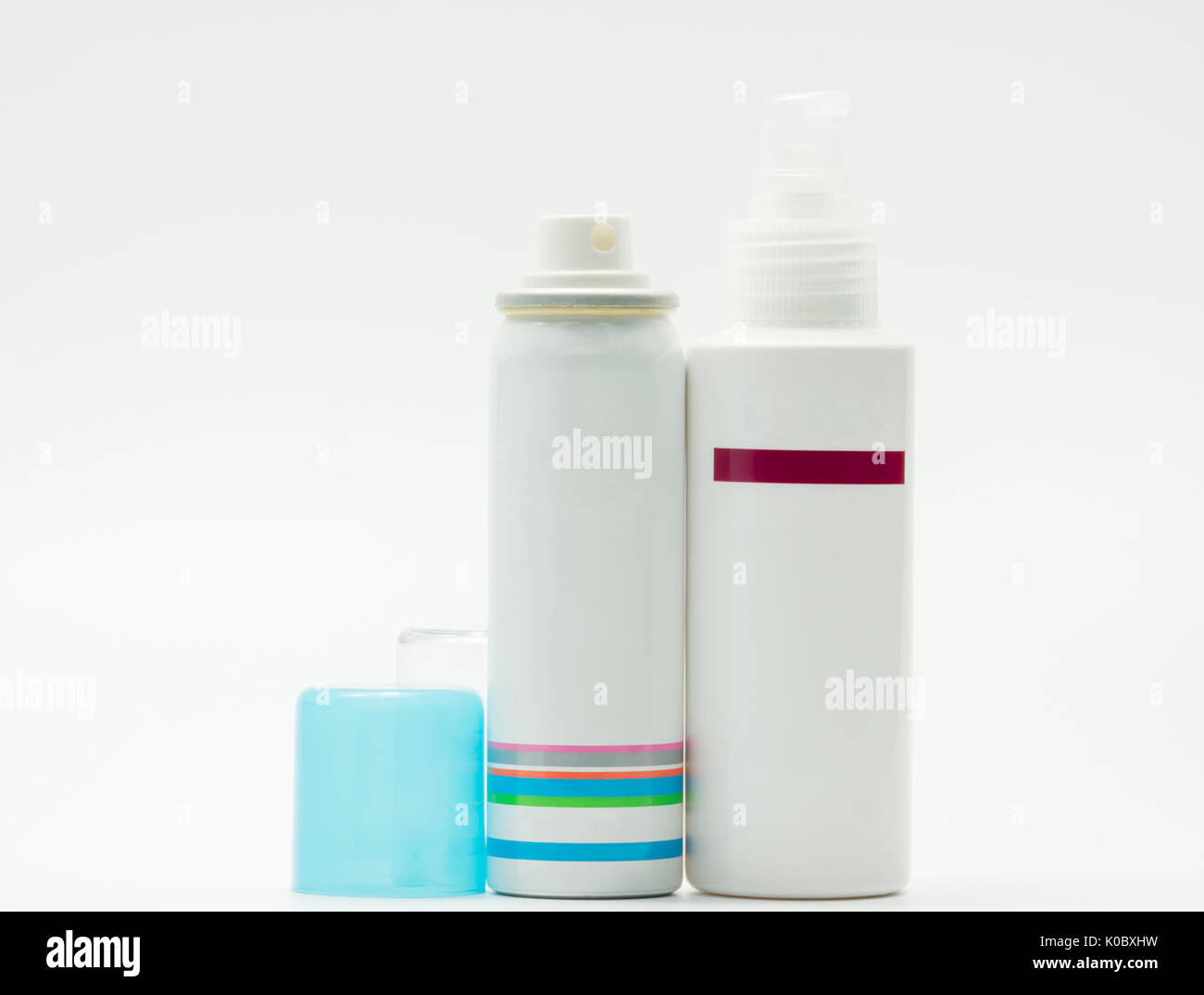 Spray bottle with opened blue cap and pump bottle of skincare on white