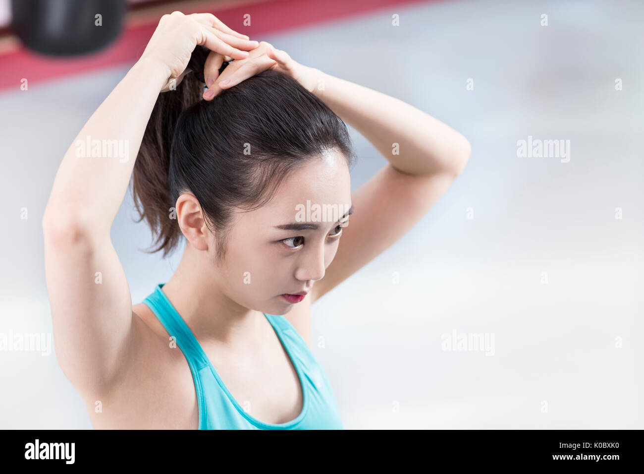 Portrait Of Young Woman In Sportswear Tying Her Hair Back Stock