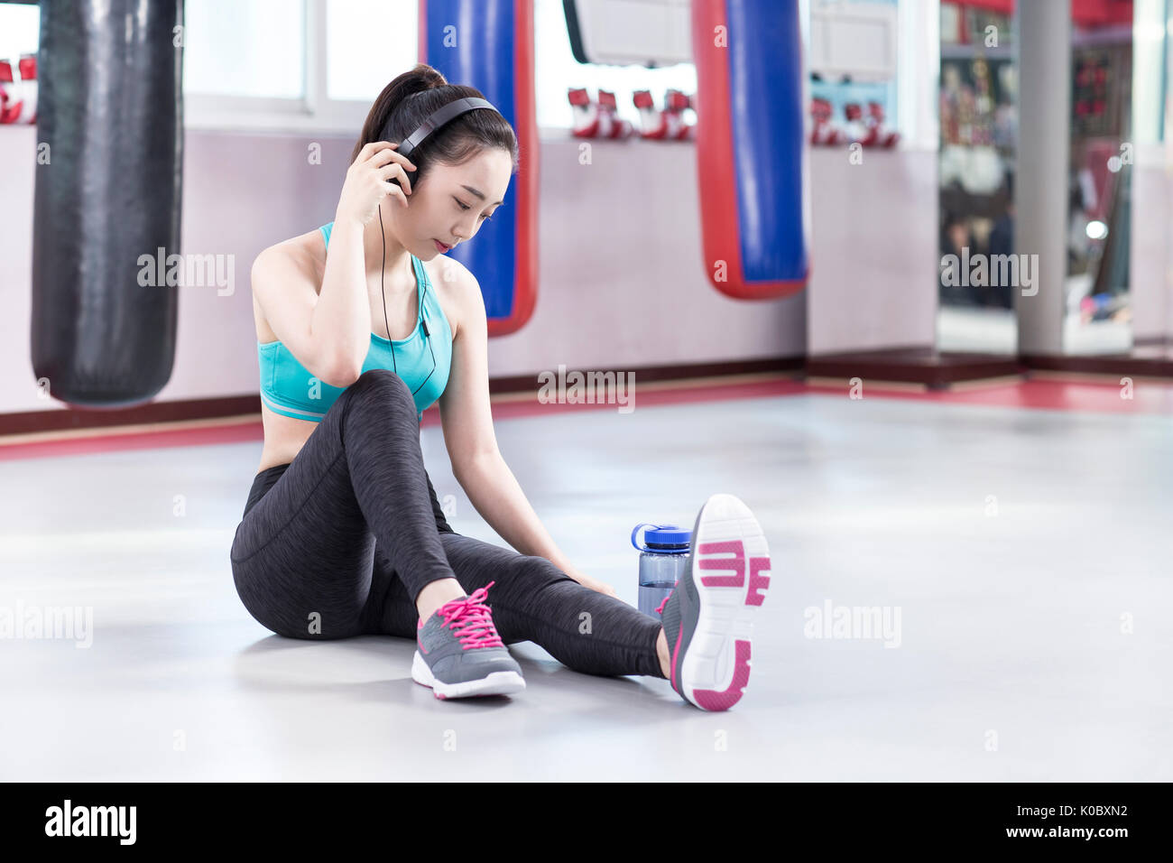 Young woman in sportswear resting sitting on floor at health club Stock Photo
