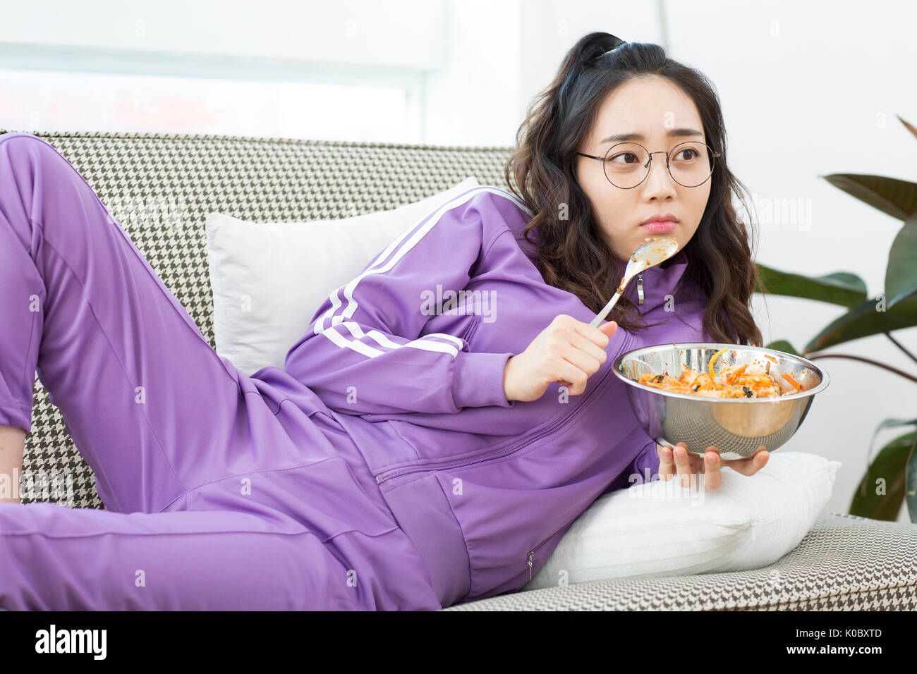 Young NEET woman watching TV eating meal Stock Photo