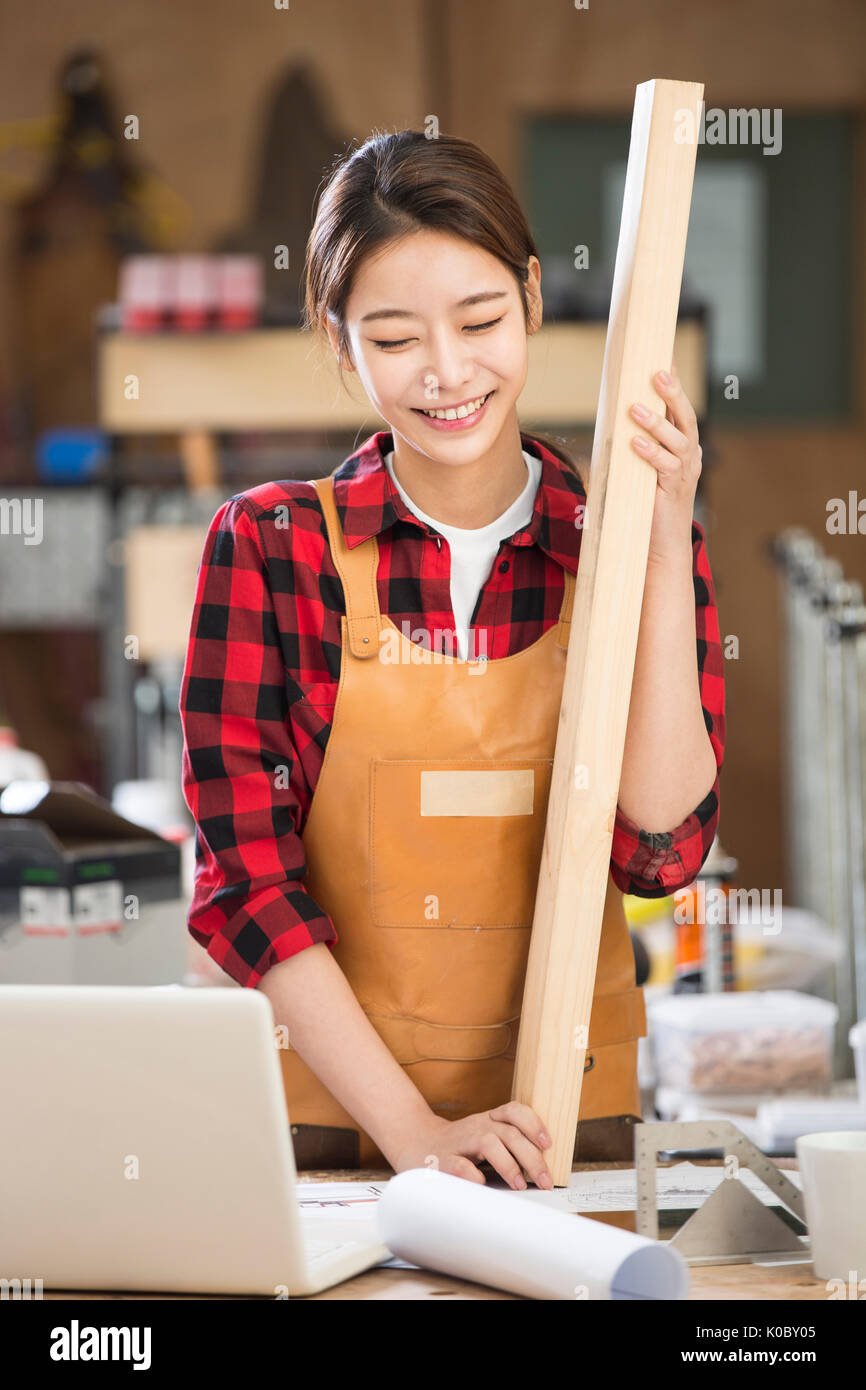 Young smiling female furniture designer holding wood Stock Photo