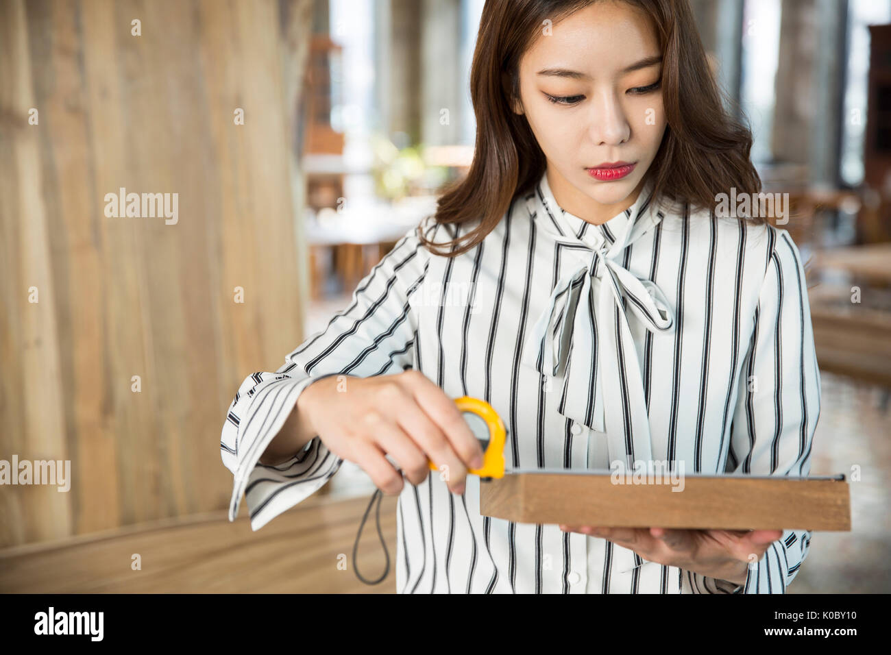Portrait of young businesswoman measuring wood Stock Photo