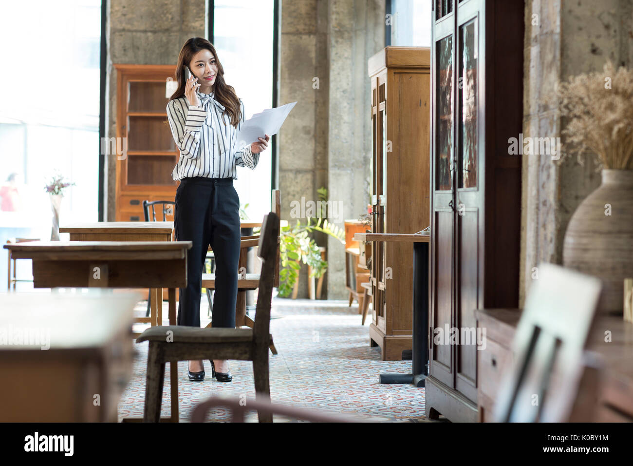 Young smiling female furniture expert talking on cellphone at shop Stock Photo