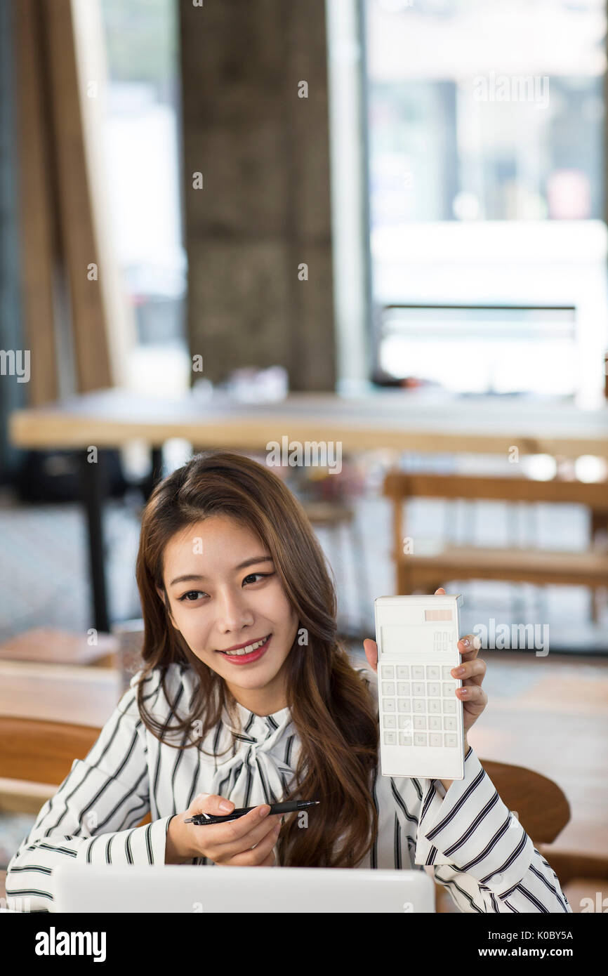 Portrait of young smiling businesswoman with calculator dealing with customer at furniture store Stock Photo