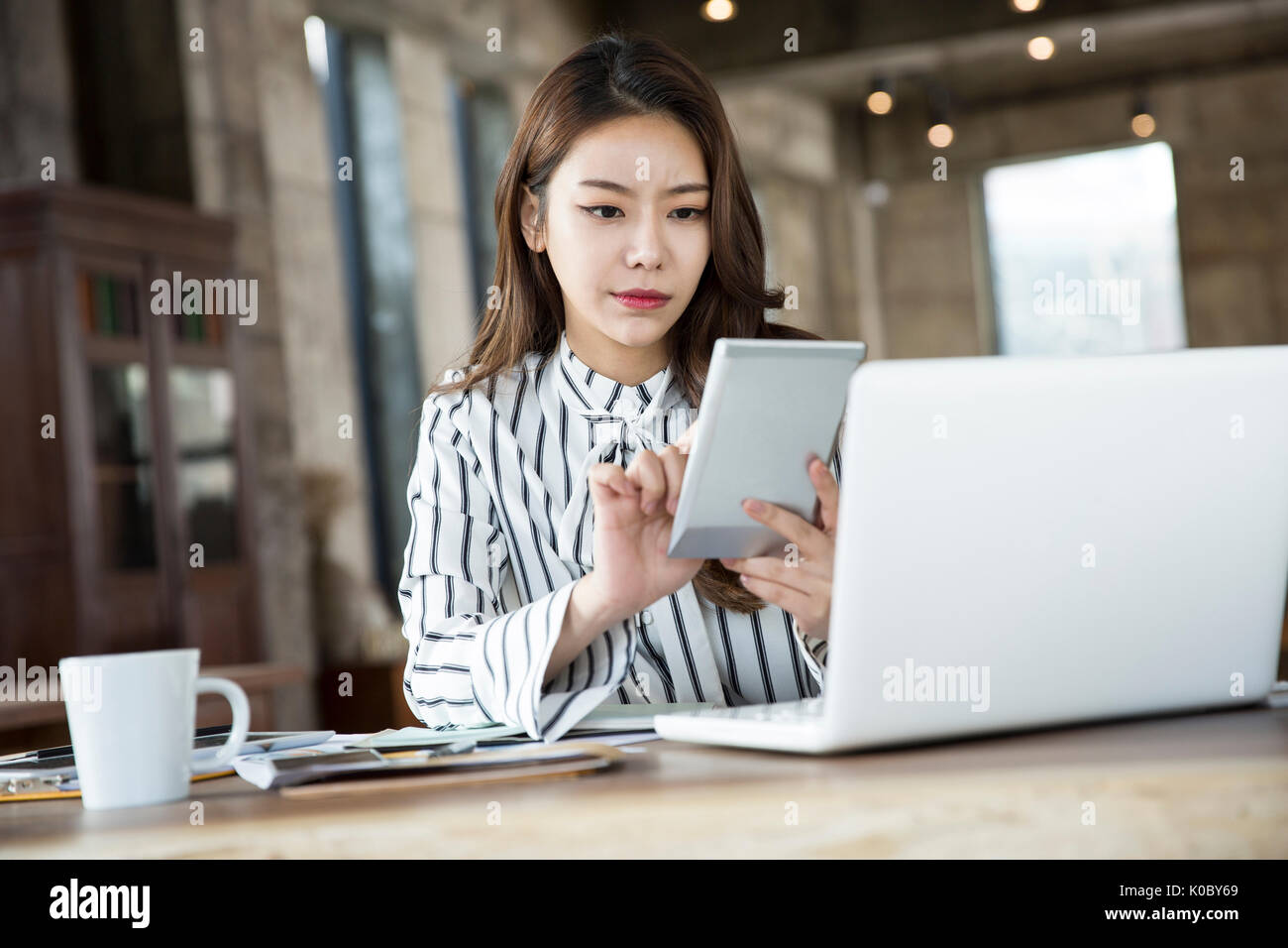 Portrait of young businesswoman using calculator at furniture store Stock Photo