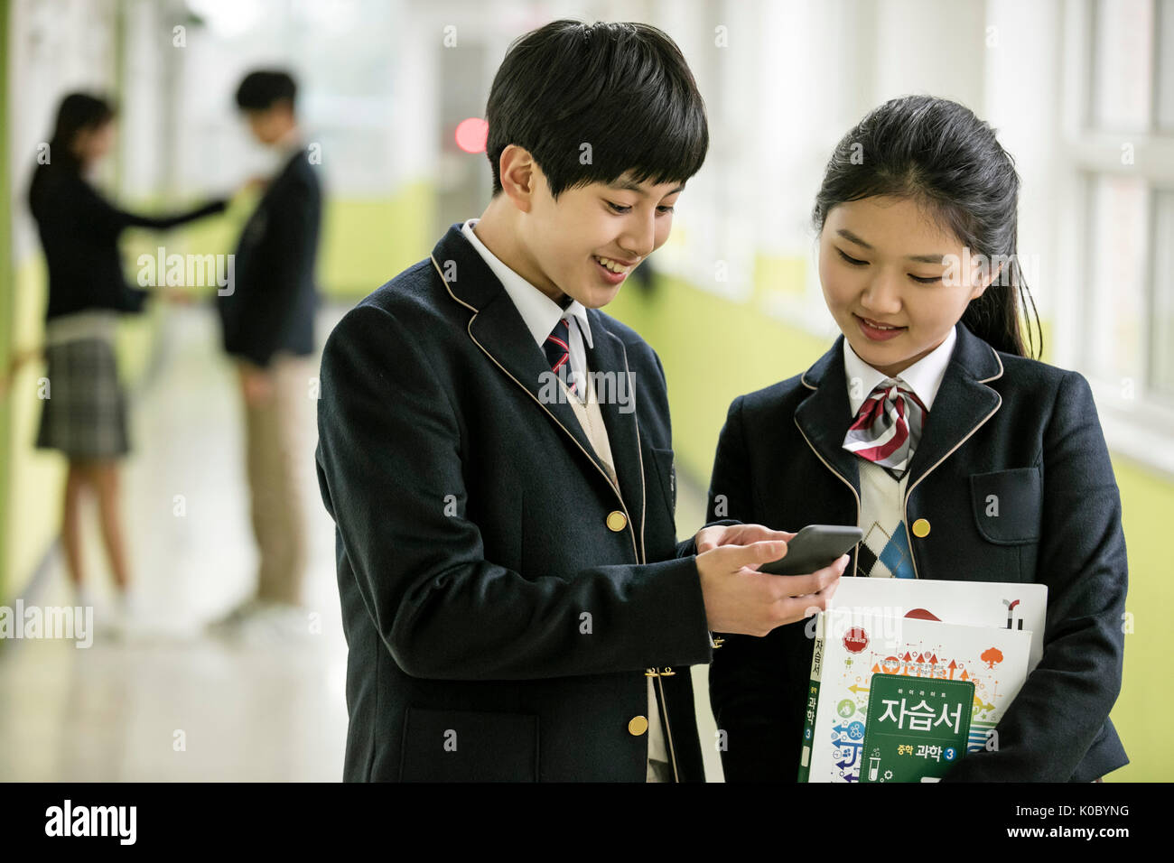 Smiling school boy and school girl sharing a smartphone Stock Photo