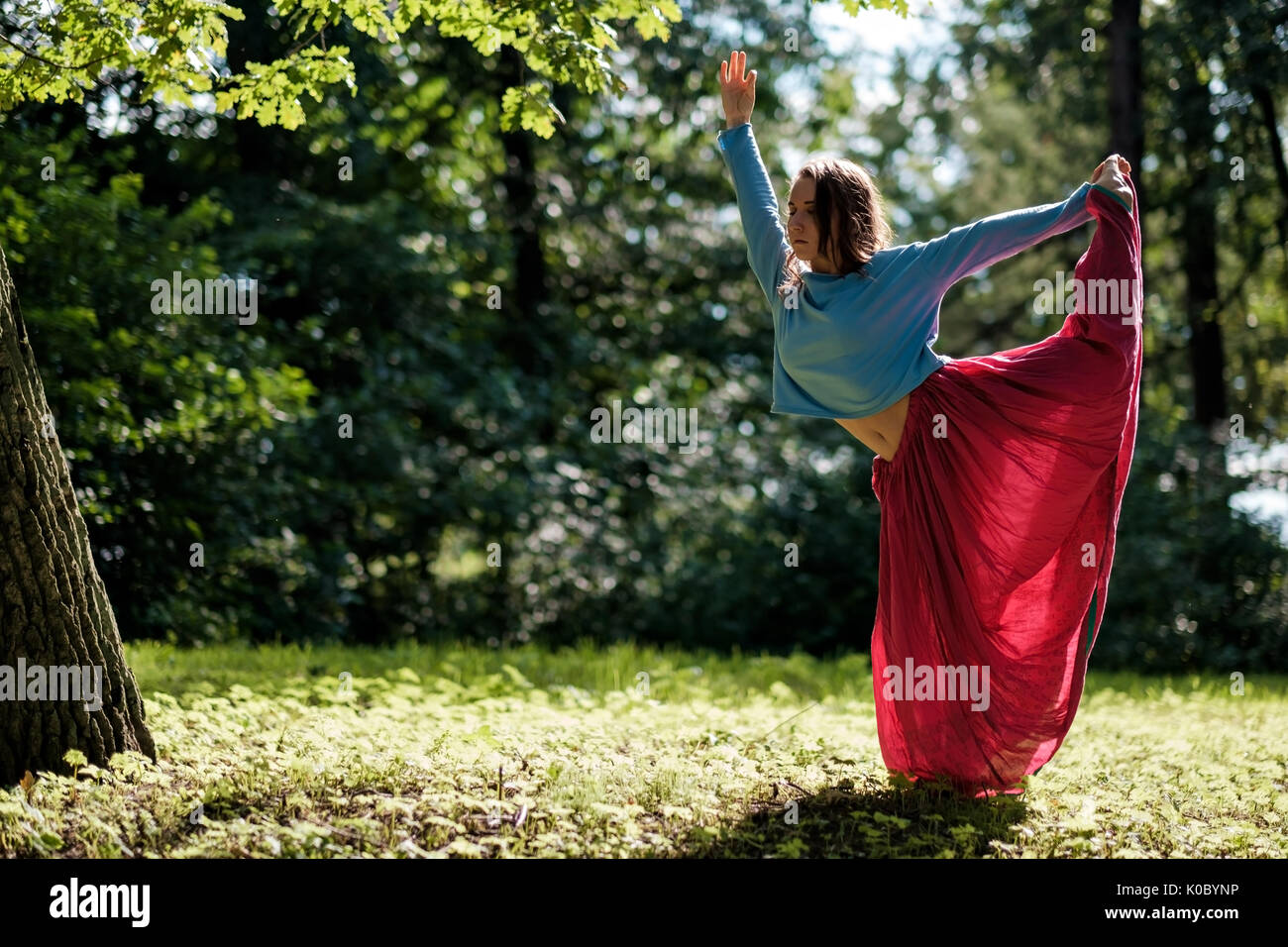 Sporty fit caucasian woman doing asana Virabhadrasana 2 Warrior pose posture in nature. Stock Photo