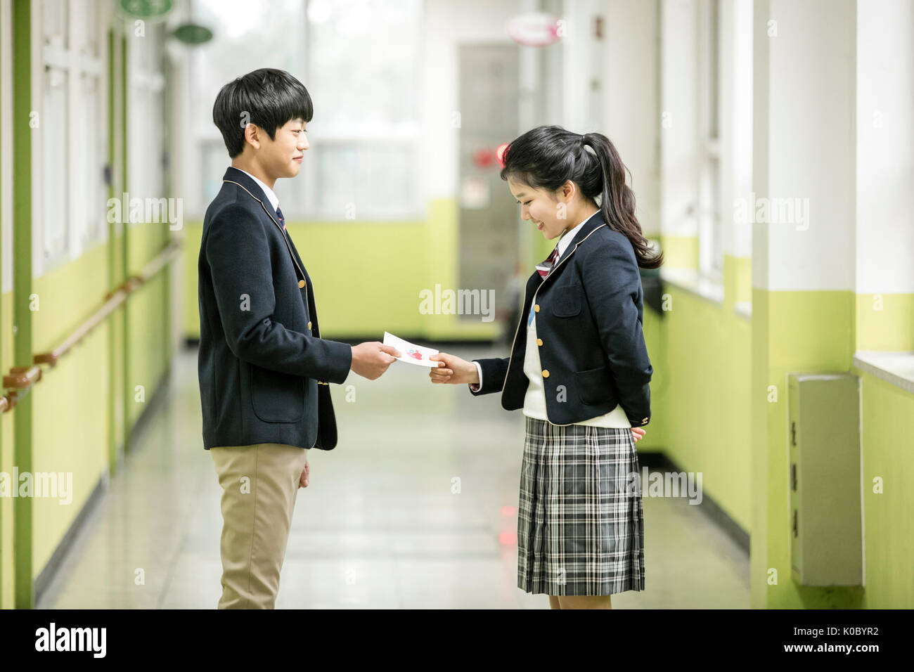 Side view of school boy and school girl passing a card at school Stock Photo