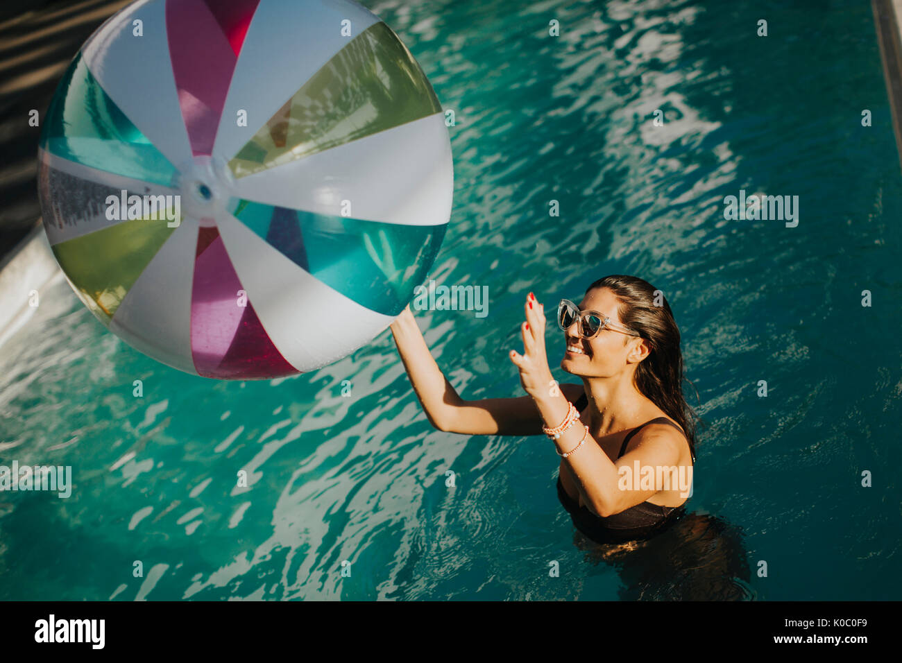 Young womans playing with a ball in the swimming pool at sunny day ...