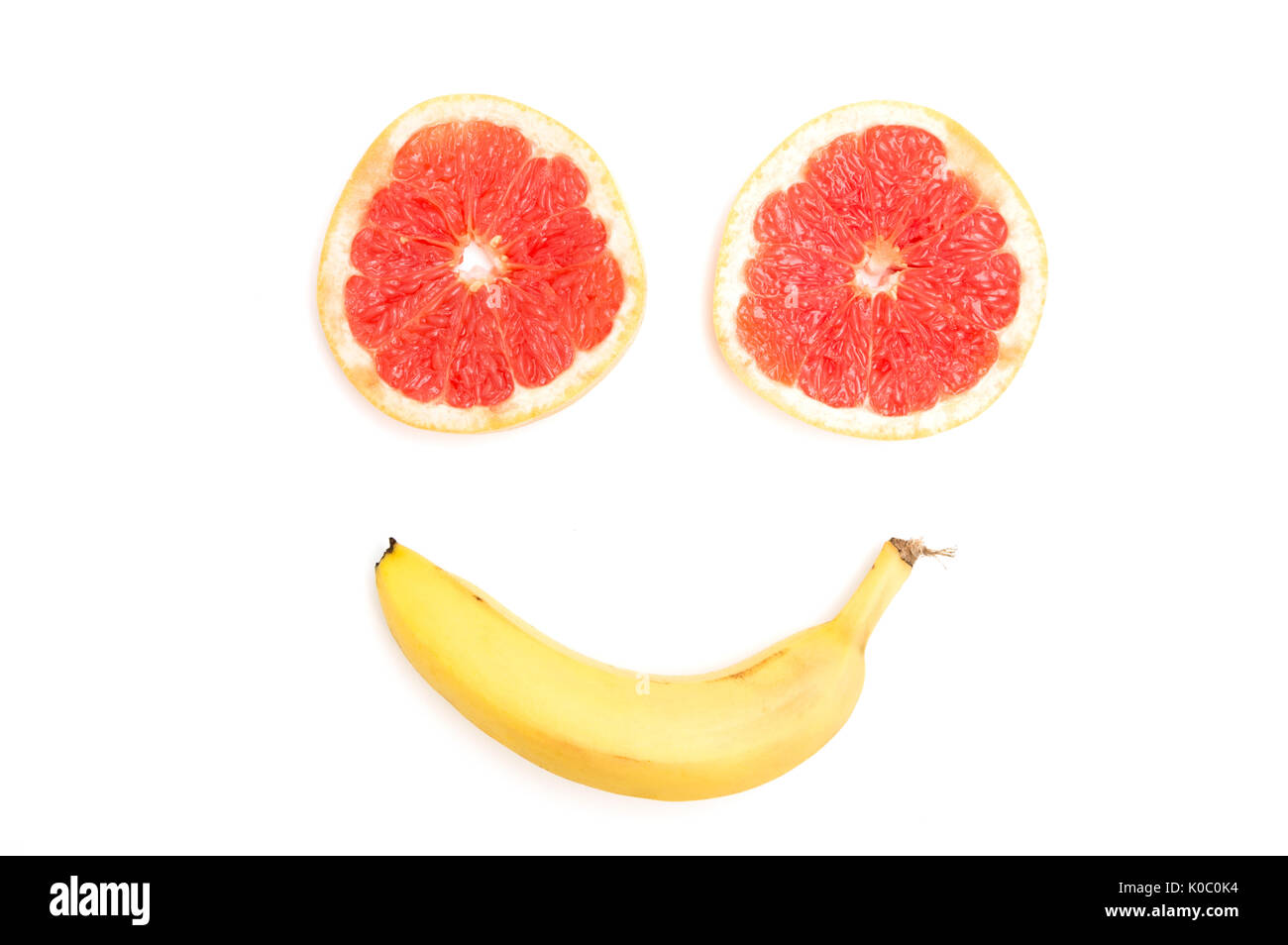 Smiling face made from grapefruit and banana on white background Stock Photo