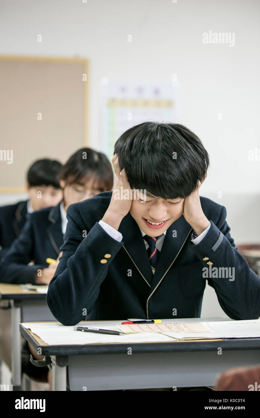 Portrait of stressful Korean school boy in classroom Stock Photo