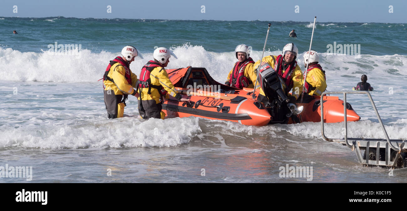 Members of St Agnes lifeboat crew launching the inshore rescue boat at Trevaunance Cove, Saint Agnes, Cornwall, England, UK Stock Photo