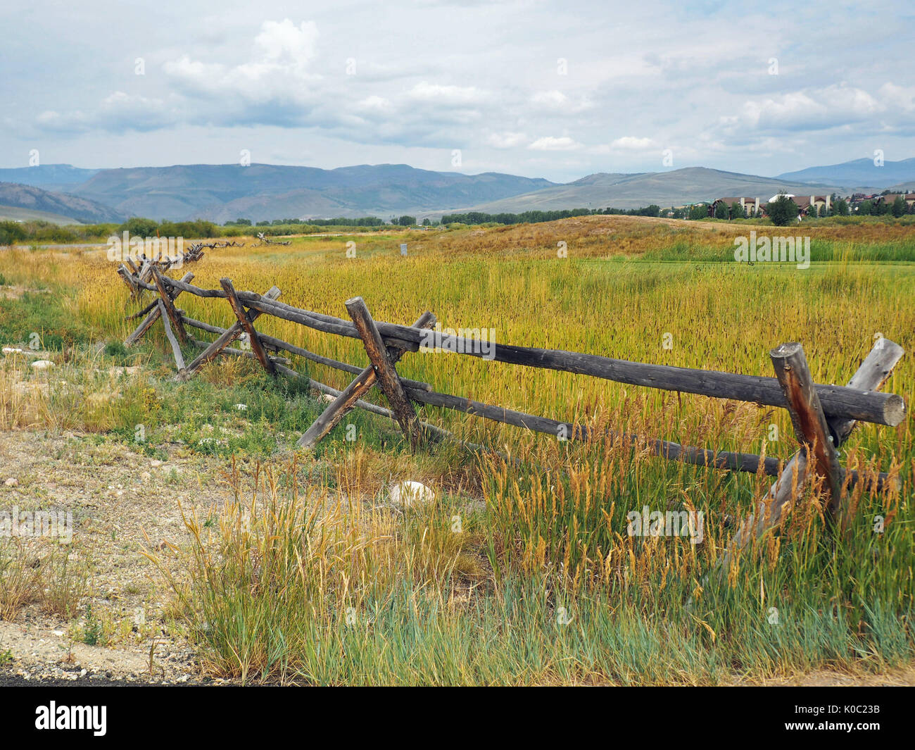 A log fence by a prairie in Colorado.   In the background are the Rocky Mountains. Stock Photo