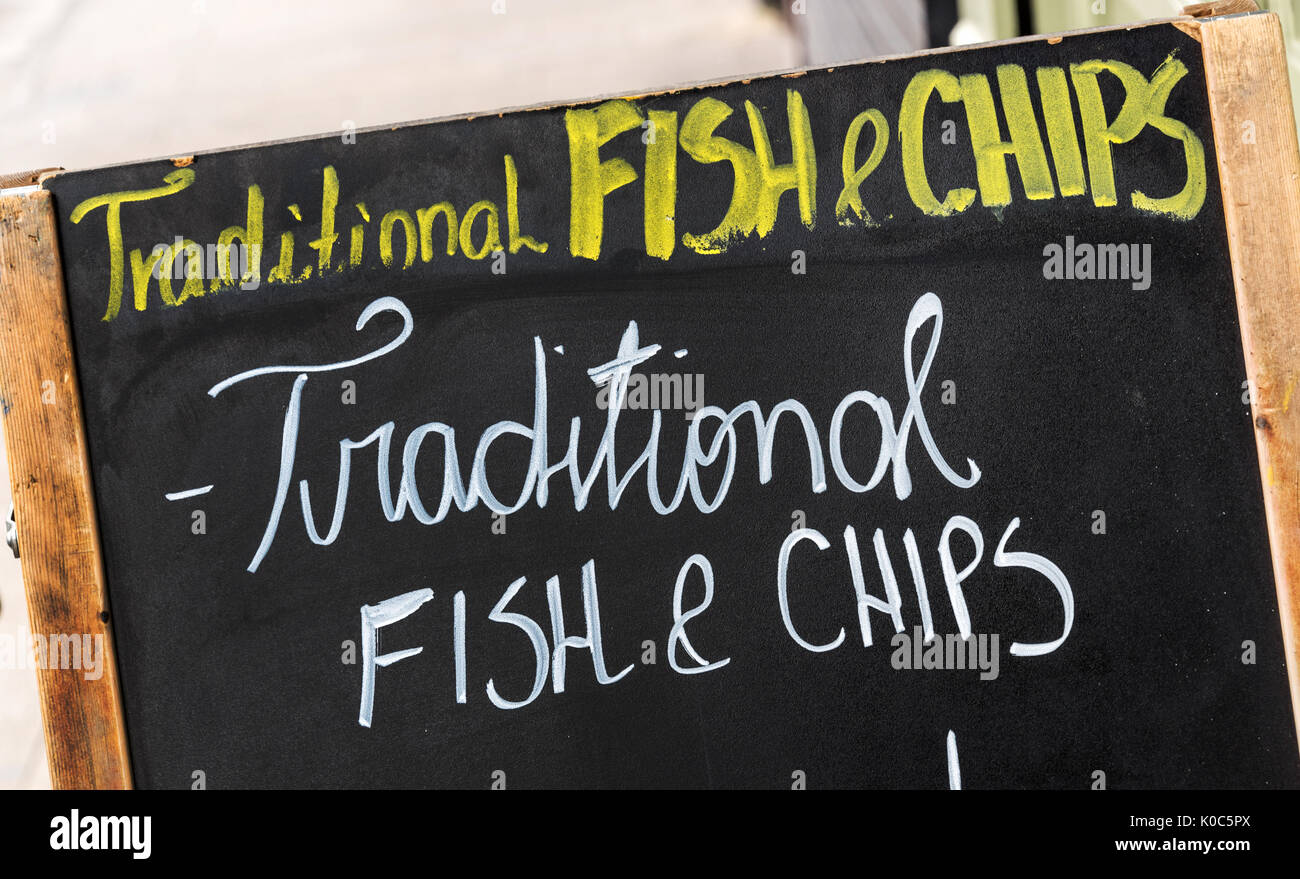 Close up on a fish and chips sign, text Traditional fish and chips written on a blackboard in the street Stock Photo