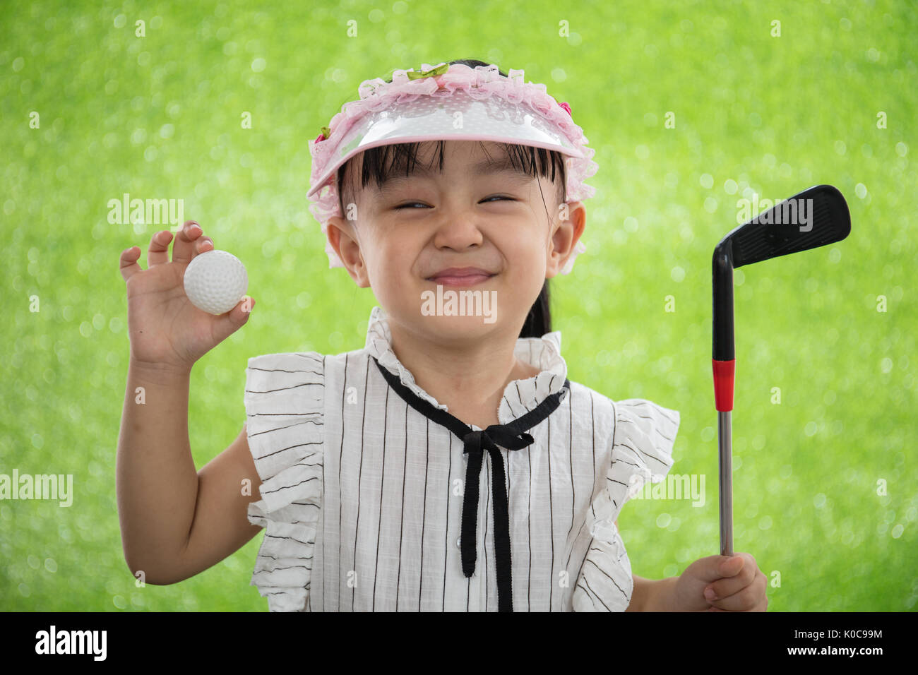 Asian Chinese little girl holding a golf ball on green grass Stock