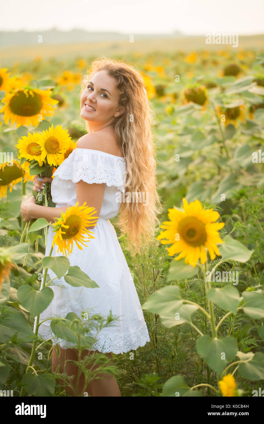 Young woman in a field of sunflowers. sunset light in the field of ...