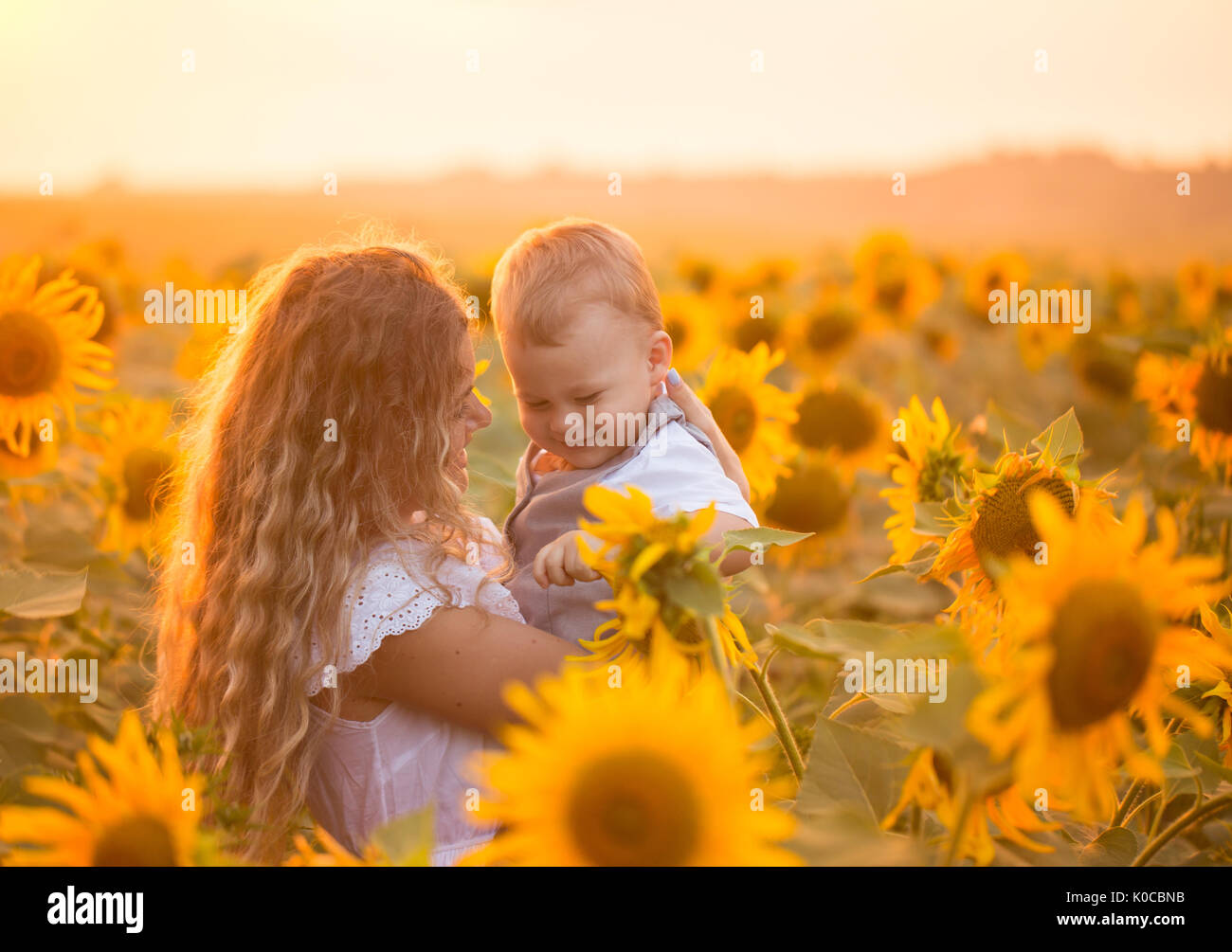 Mother with baby son in sunflower field Stock Photo - Alamy