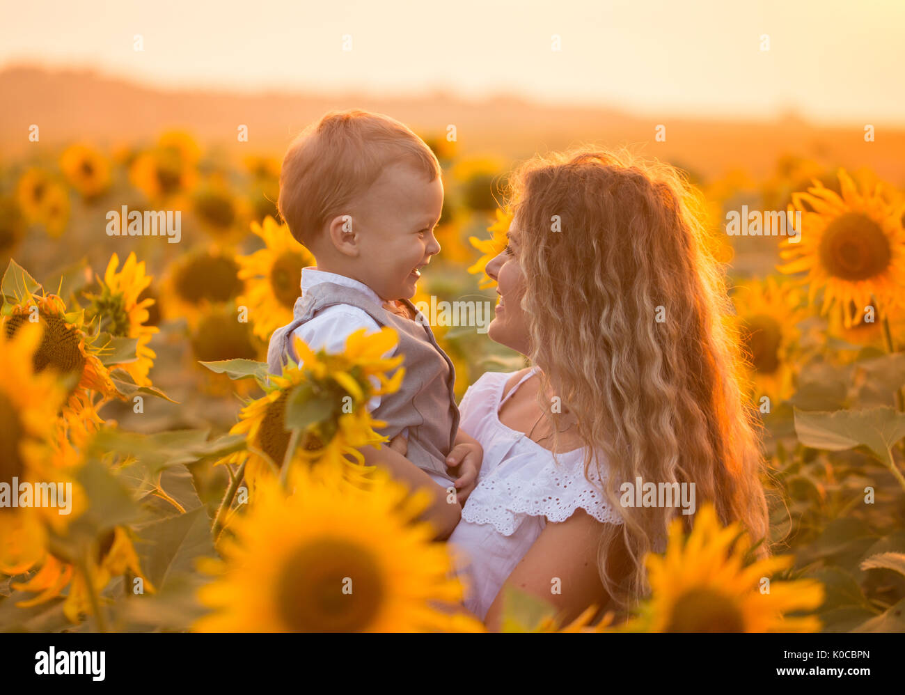 Mother with baby son in sunflower field Stock Photo - Alamy