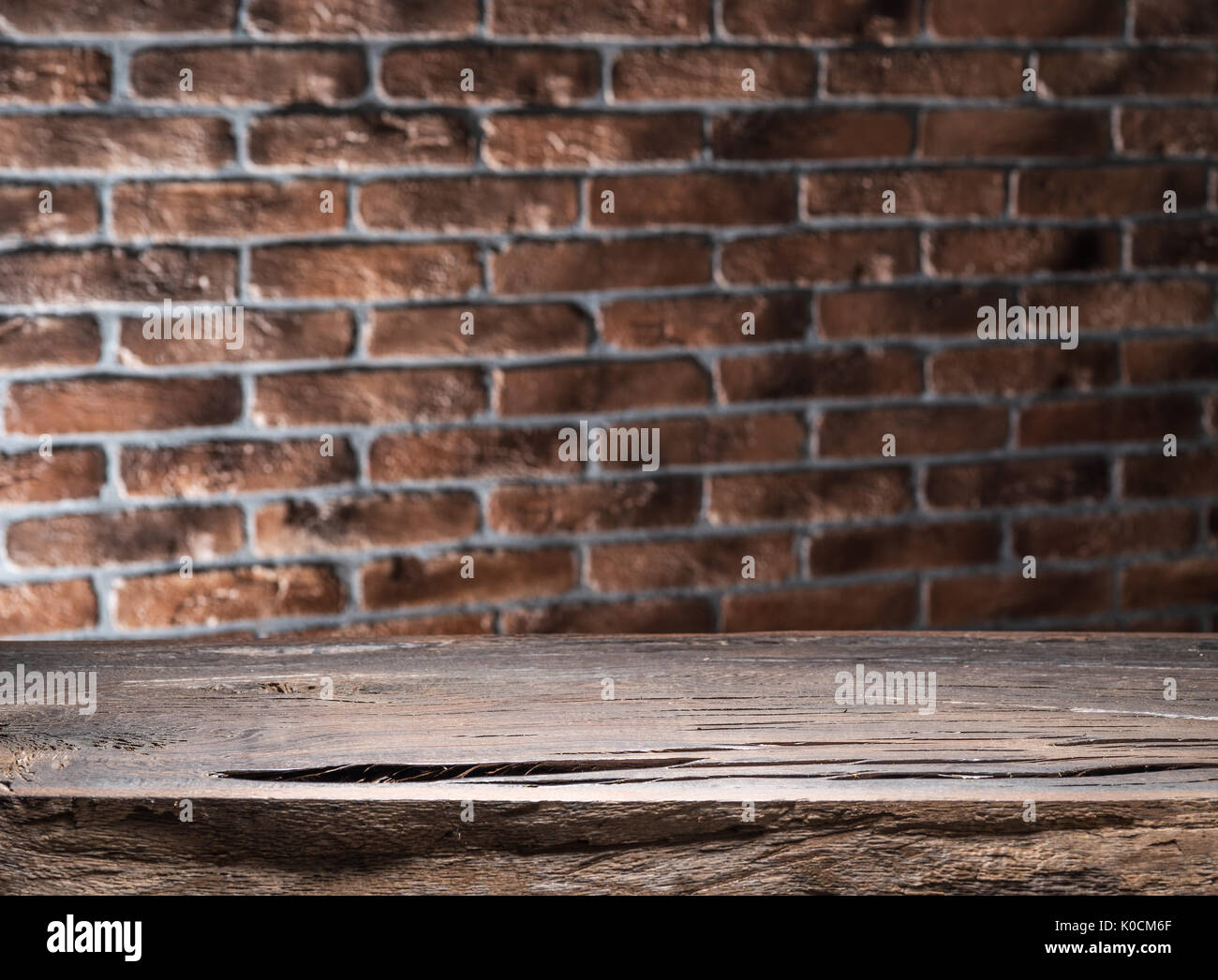 Old wooden empty table and brick wall in the background. Stock Photo