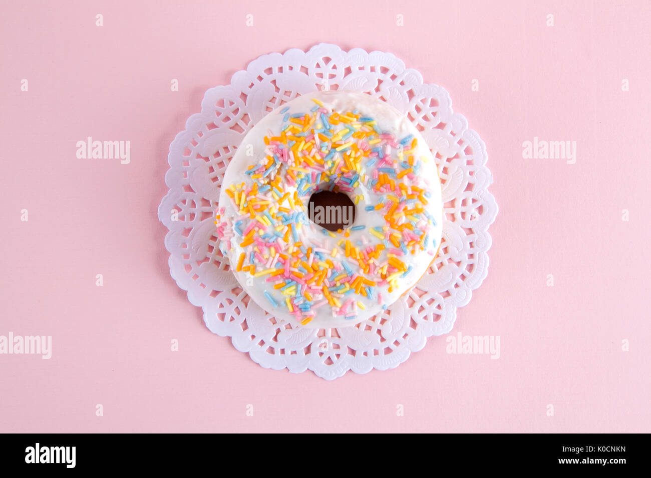 a multicolor donuts presented on a doily paper and a pop colorful background. Stock Photo