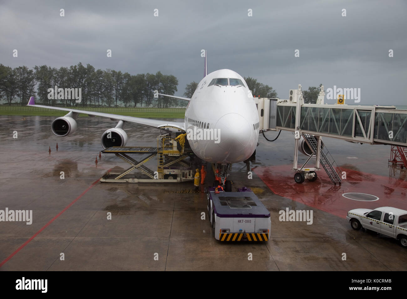 A Thai airways 747 jumbo being loaded at Phuket airport in heavy rain ...