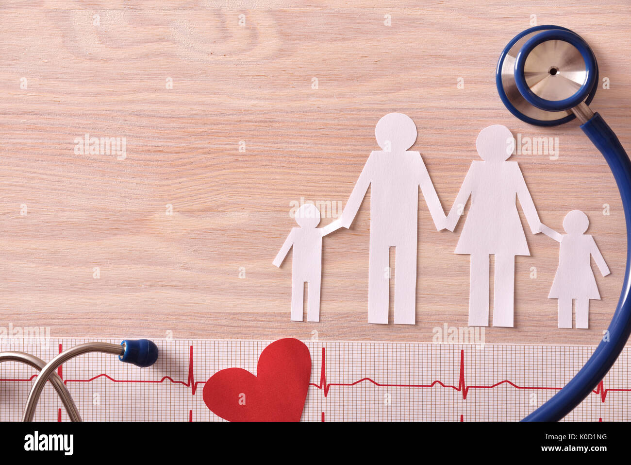 Electrocardiogram stethoscope and paper cutout heart and family on wood table. Top view. Horizontal composition. Stock Photo