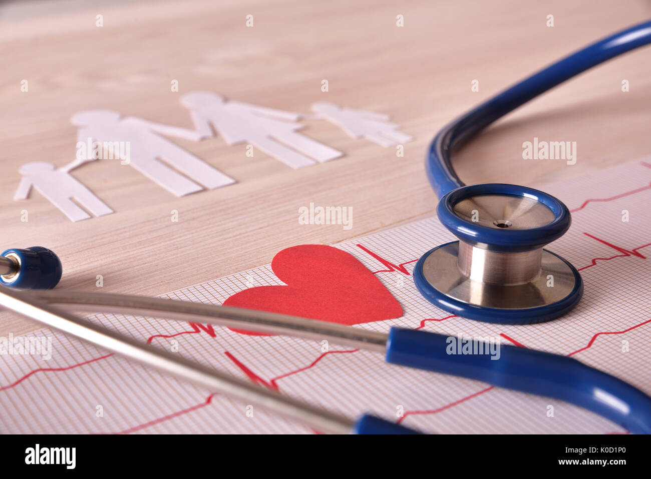Electrocardiogram stethoscope and paper cutout heart and family on wood table. Elevated view. Horizontal composition. Stock Photo
