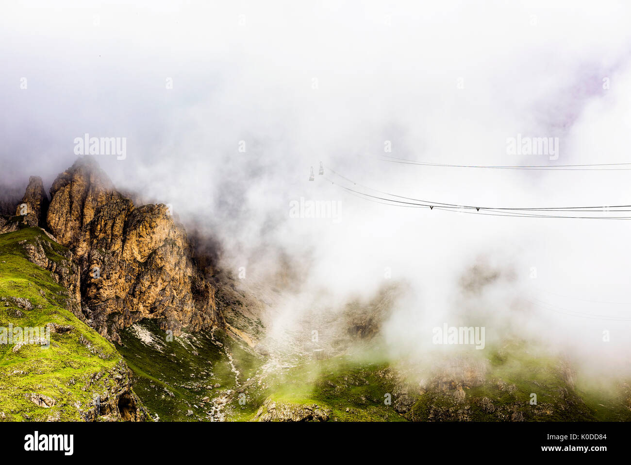 Sass Pordoi is one of the most visited mountains of the Dolomites. A cable-car, just visible as it enters the clouds, leads up from the road pass. Stock Photo