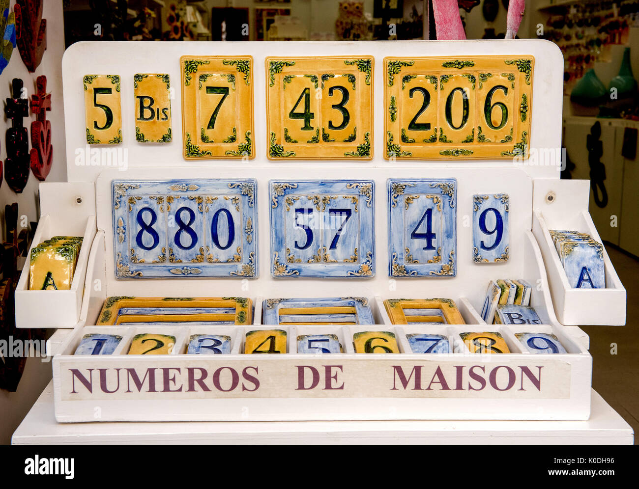 Handmade ornamental ceramic house numbers on display in a box in yellow and blue for sale in a French shop Stock Photo