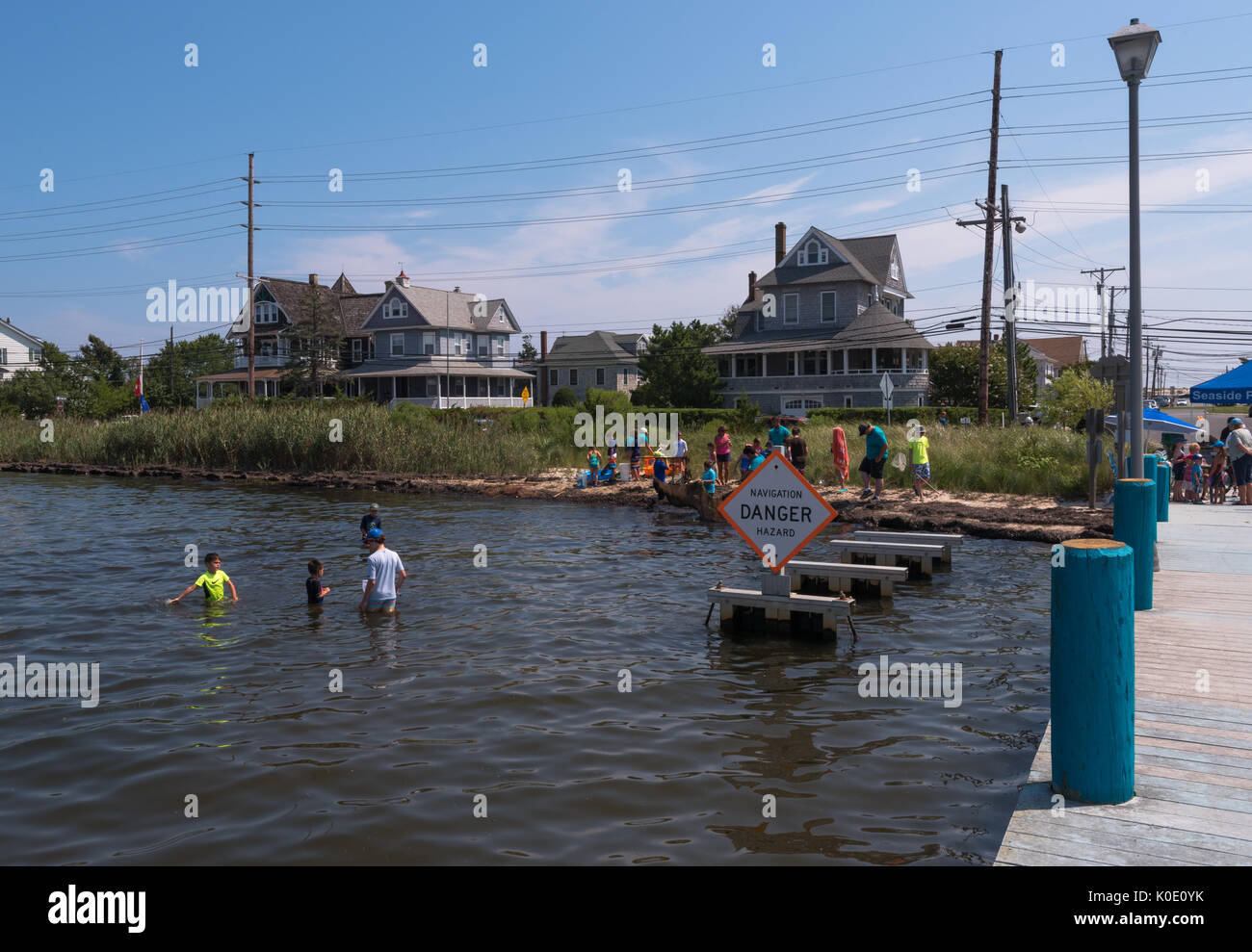 Seaside Heights, NJ USA -- August 21, 2017 Young people are crabbing in shallow waters by a danger sign at the Jersey Shore. Editorial Use Only Stock Photo