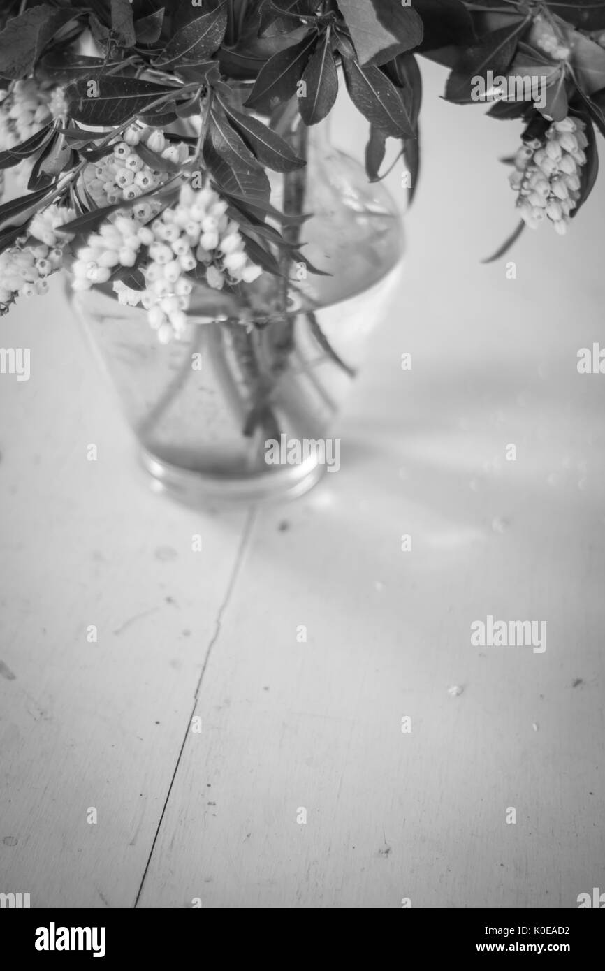Black and white floral display on a painted wooden table. Stock Photo