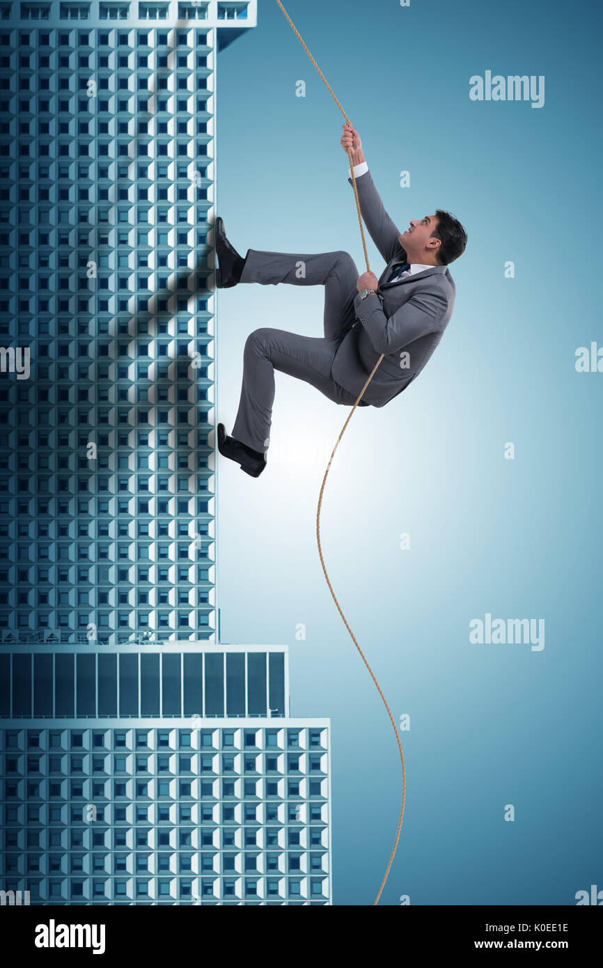 Businessman climbing skyscraper in challenge concept Stock Photo