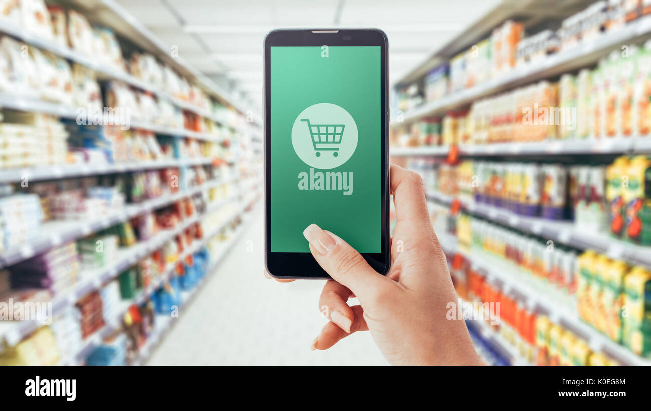 Woman doing grocery shopping at the supermarket, she is purchasing items  with a smartphone: augmented reality and commerce concept Stock Photo -  Alamy