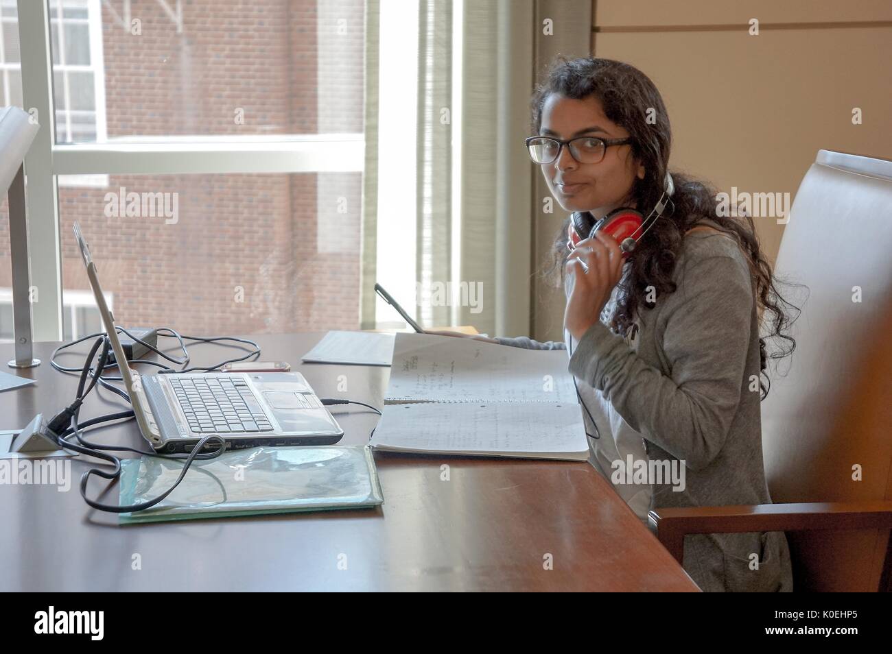 A female Johns Hopkins University student studies in the Brody Reading Room at the Brody Learning Commons with her laptop and notebooks in front of her with red headphones around her neck at Johns Hopkins University, Baltimore, Maryland, 2013. Courtesy Eric Chen. Stock Photo