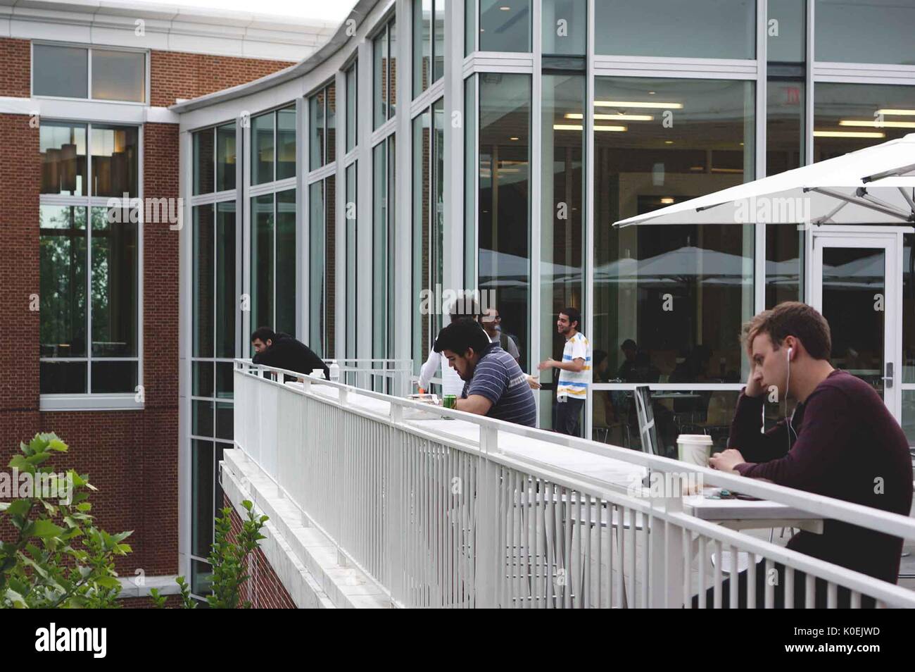 During finals period in May 2014, college students study, drink coffee, and socialize on the patio area outside of the Brody Learning Commons, an interactive/collaborative study space and library on the Homewood campus of the Johns Hopkins University in Baltimore, Maryland. 2014. Courtesy Eric Chen. Stock Photo