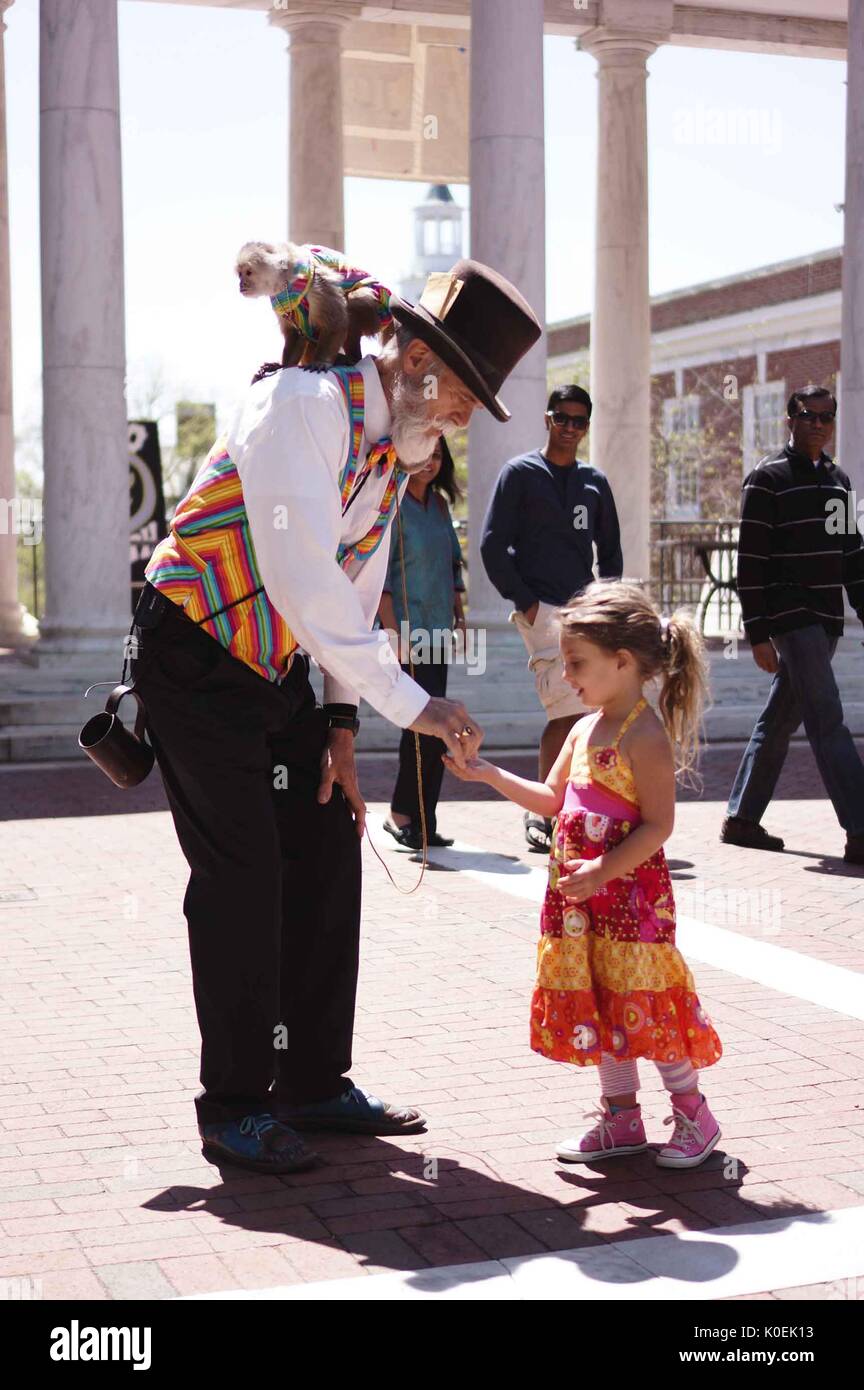 A entertainer with a monkey on his back interacts with a young child during Spring Fair, an annual festival with music, food, shopping, and more that takes place every spring on the Homewood campus of the Johns Hopkins University in Baltimore, Maryland. 2014. Courtesy Eric Chen. Stock Photo