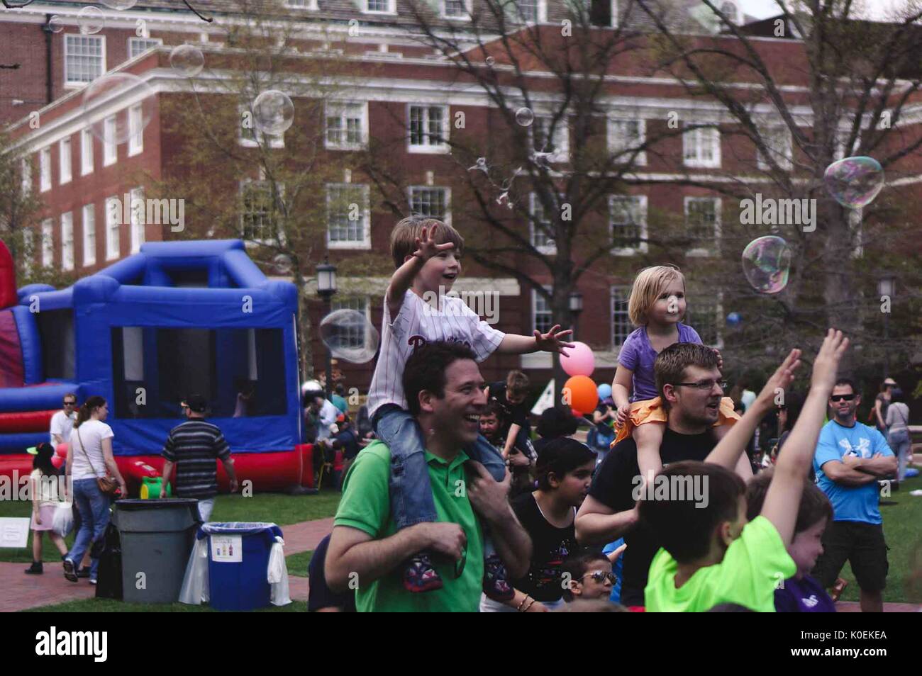 Families play near inflatables set up for Spring Fair, an annual festival with music, food, shopping, and more that takes place every spring on the Homewood campus of the Johns Hopkins University in Baltimore, Maryland, 2014. Courtesy Eric Chen. Stock Photo