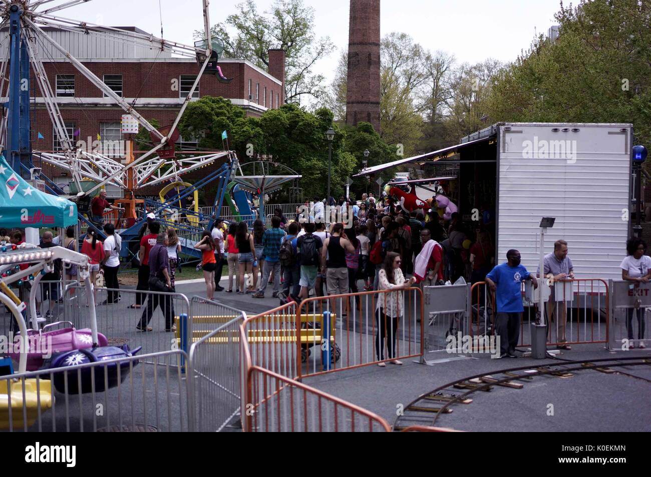 A crowd of people onlooking and waiting in line for various aerial carnival rides set up behind the Milton S. Eisenhower Library for Spring Fair, a student-run Spring carnival, at Johns Hopkins University, Baltimore, Maryland, April, 2015. Courtesy Eric Chen. Stock Photo