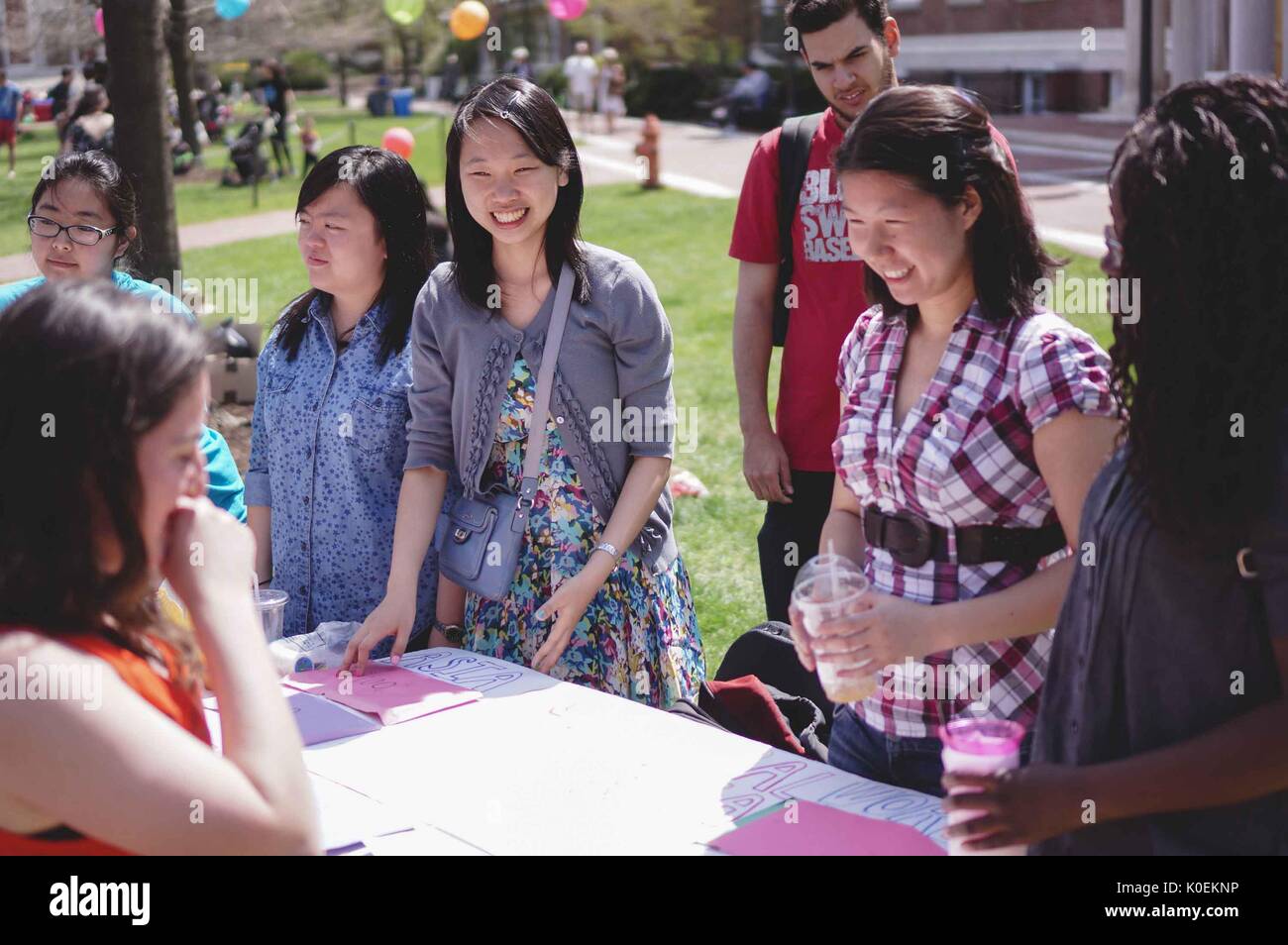 Female students at Johns Hopkins University happily engage with a woman running a stand on Keyser Quad at Spring Fair, a student-run Spring carnival, on a bright sunny day at Johns Hopkins University, Baltimore, Maryland, April, 2015. Courtesy Eric Chen. Stock Photo