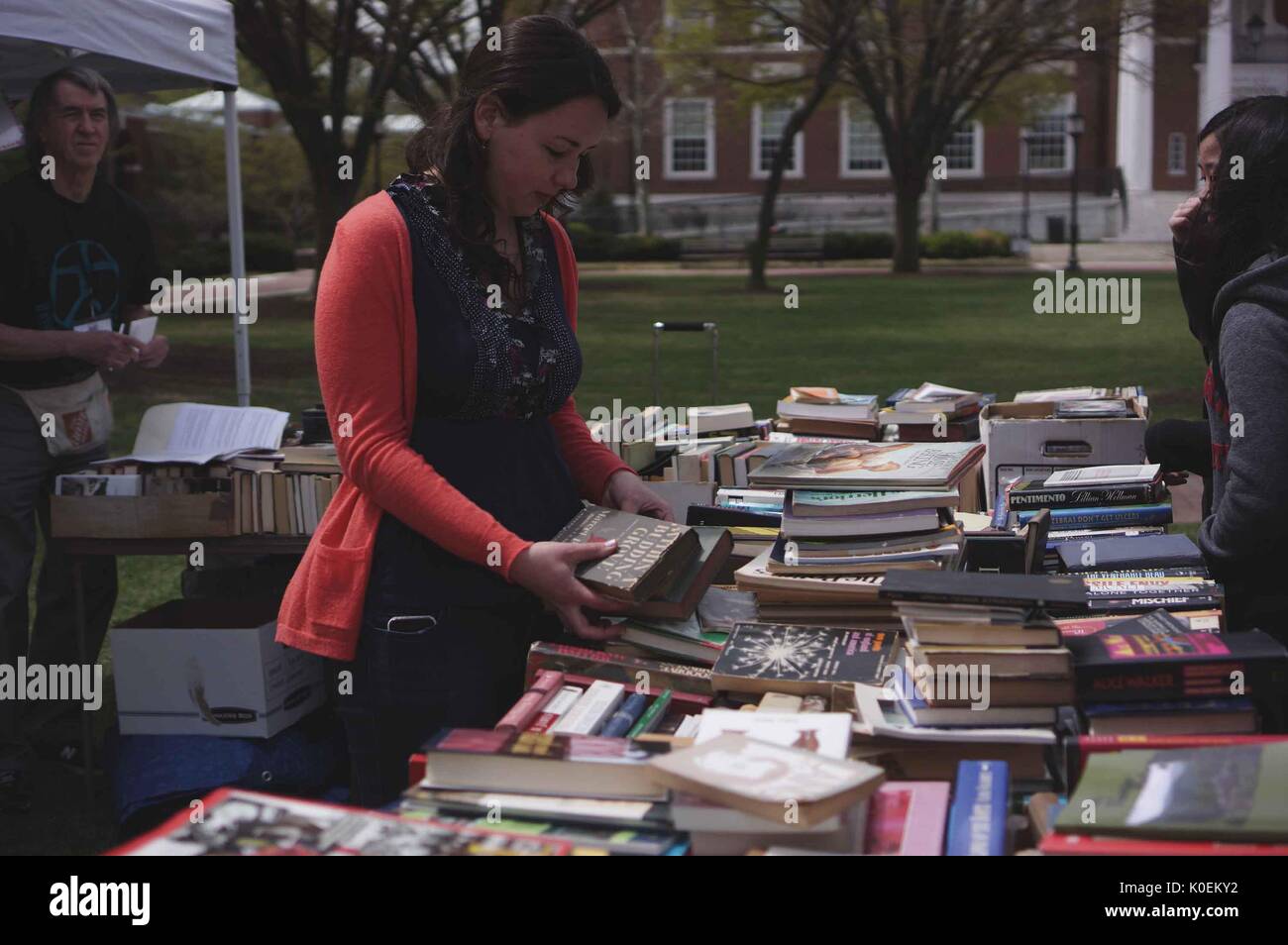 College students and members of the Johns Hopkins and Baltimore communities look through books that have been set up by a vendor for Spring Fair, an annual festival with music, food, shopping, and more that takes place every spring on the Homewood campus of the Johns Hopkins University in Baltimore, Maryland, April, 2014. Courtesy Eric Chen. Stock Photo