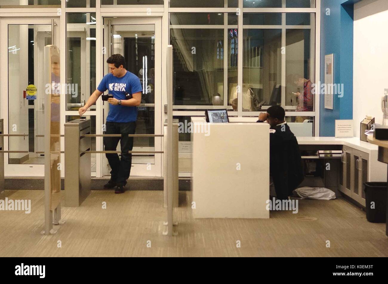 A college student swipes his access card at the guard station to come into Brody Learning Commons, 2015. Courtesy Eric Chen. Stock Photo