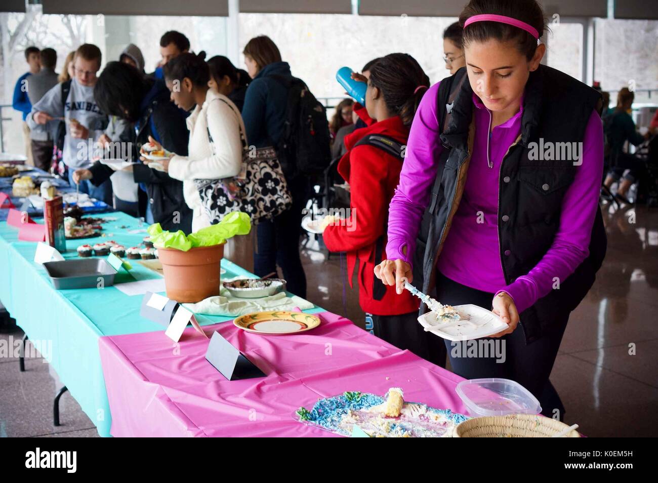 College students crowd around the long table to try various types of cake at the Edible Book Festival, April, 2014. Courtesy Eric Chen. Stock Photo