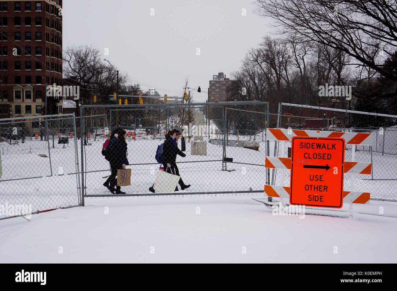 College students cross Charles street, which is covered in snow and has construction signs and fences around it, to get to the Homewood campus of the Johns Hopkins University in Baltimore, Maryland, 2014. Courtesy Eric Chen. Stock Photo