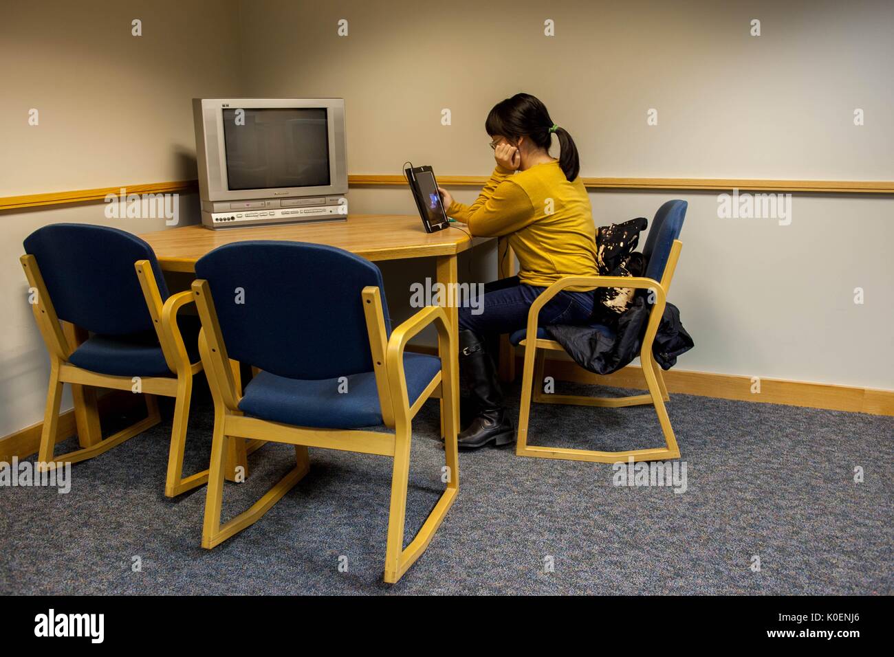 Student on iPad in Milton S. Eisenhower Library of Johns Hopkins University to juxtapose an obsolete television set with newer technology, 1996. Courtesy Eric Chen. Stock Photo