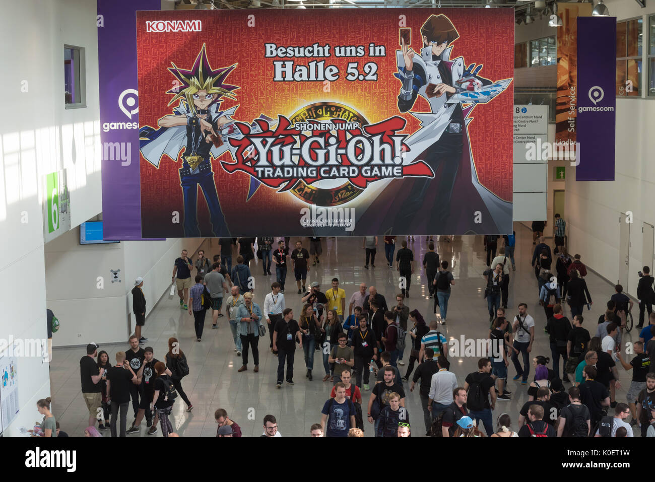 Cologne, Germany. 22nd Aug, 2017. Germany, Cologne, August 22, 2017, Gamescom: Visitors walk under Konami, yu-gi-oh, shonen jump. Credit: Juergen Schwarz/Alamy Live News Stock Photo