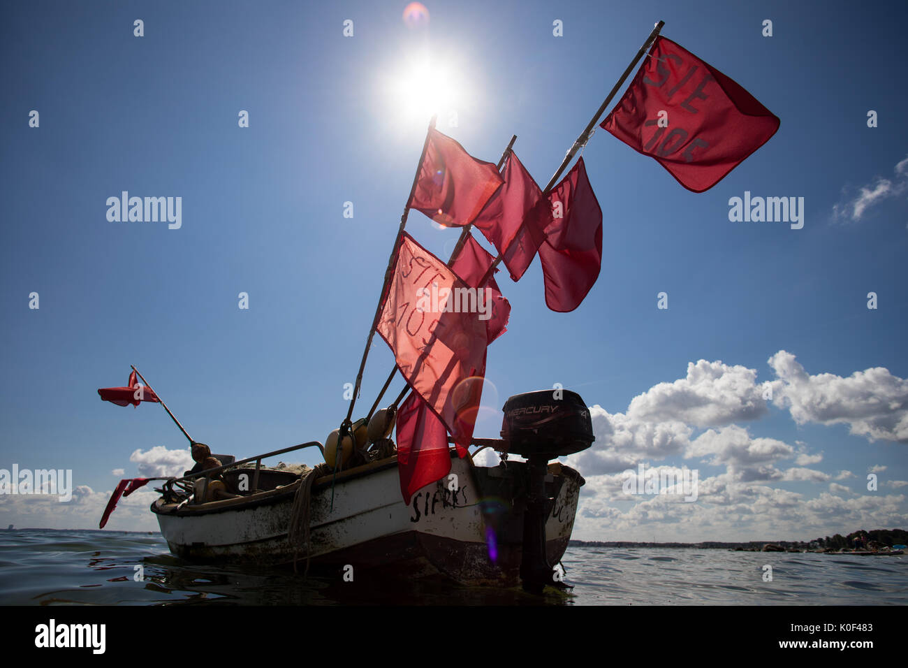 A fishing boat with red flags for the marking of nets lying at anchor
